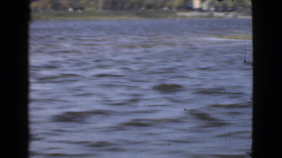 1946 Quebec 8mm frame with rippled water filling most of the view and a soft wooded shoreline in the distance.