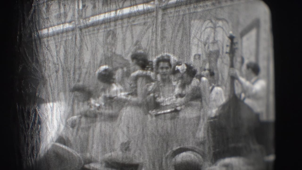 Women in hula-style costumes perform on a small stage before an audience.