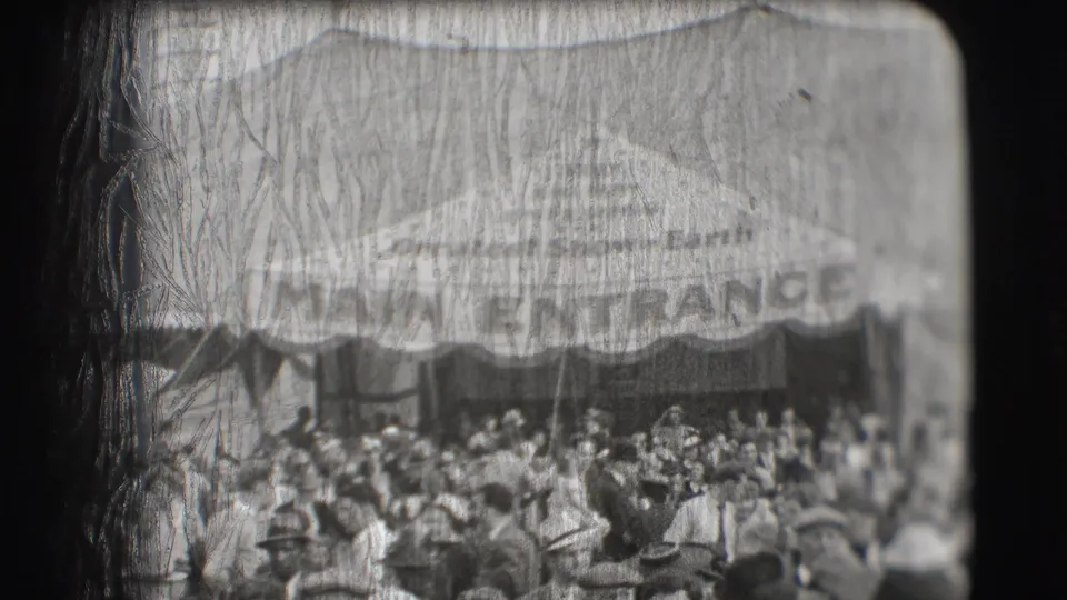 People stand and move below the Ringling Brothers circus entrance awning in Sarasota, with the MAIN ENTRANCE lettering partly visible.