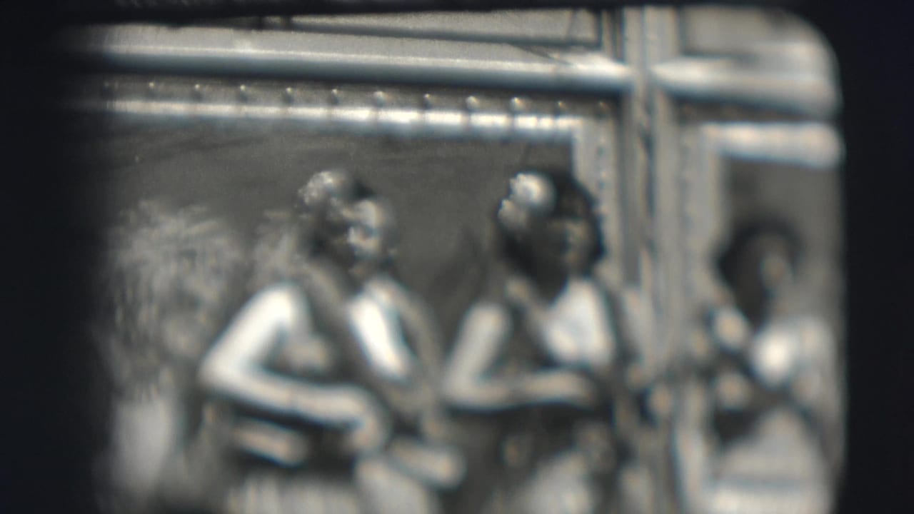 Blurred view of seated women with instruments near tent supports.
