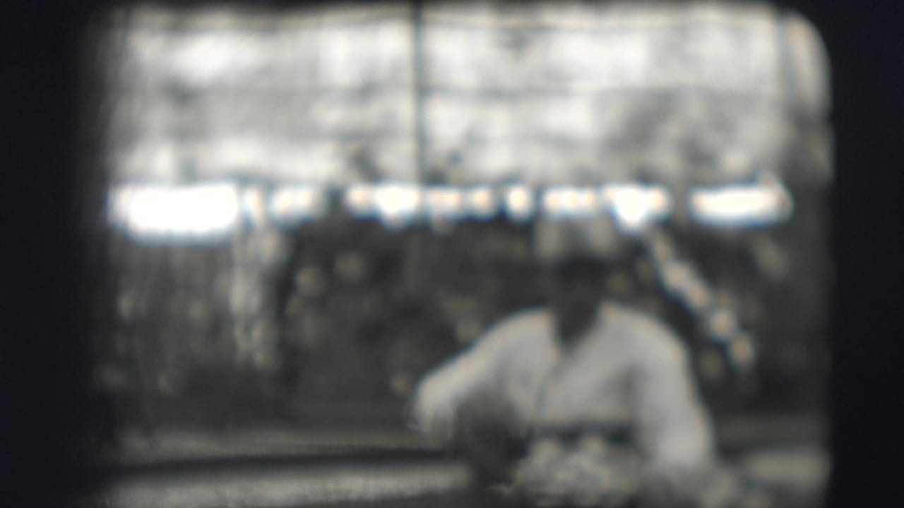 Soft-focus view of a man seated at a table with cots behind him.