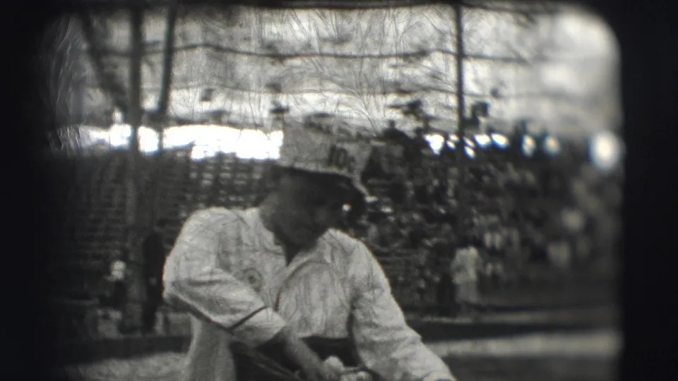 A closer 1948 home-movie view shows the uniformed man looking down toward his meal, with cots and other people behind him.