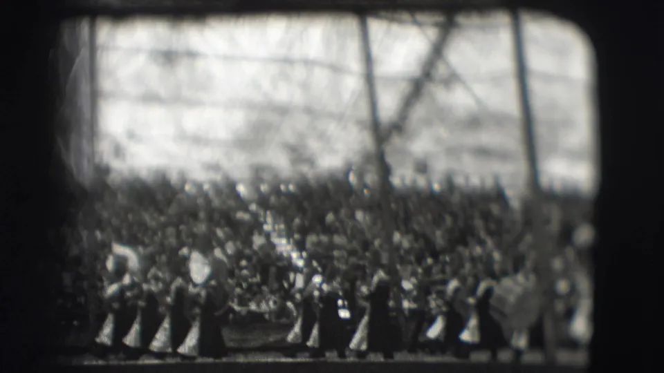 Black-and-white 8mm frame showing uniformed band members and spectators at the Sarasota Ringling Brothers parade setting described by metadata.