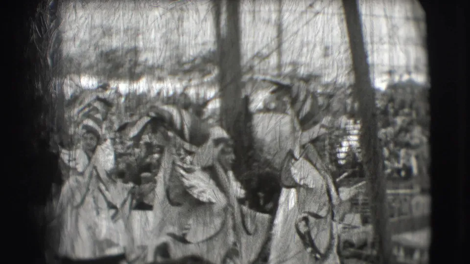 1948 Sarasota circus footage showing costumed performers near a ring act, with spectators filling the background.