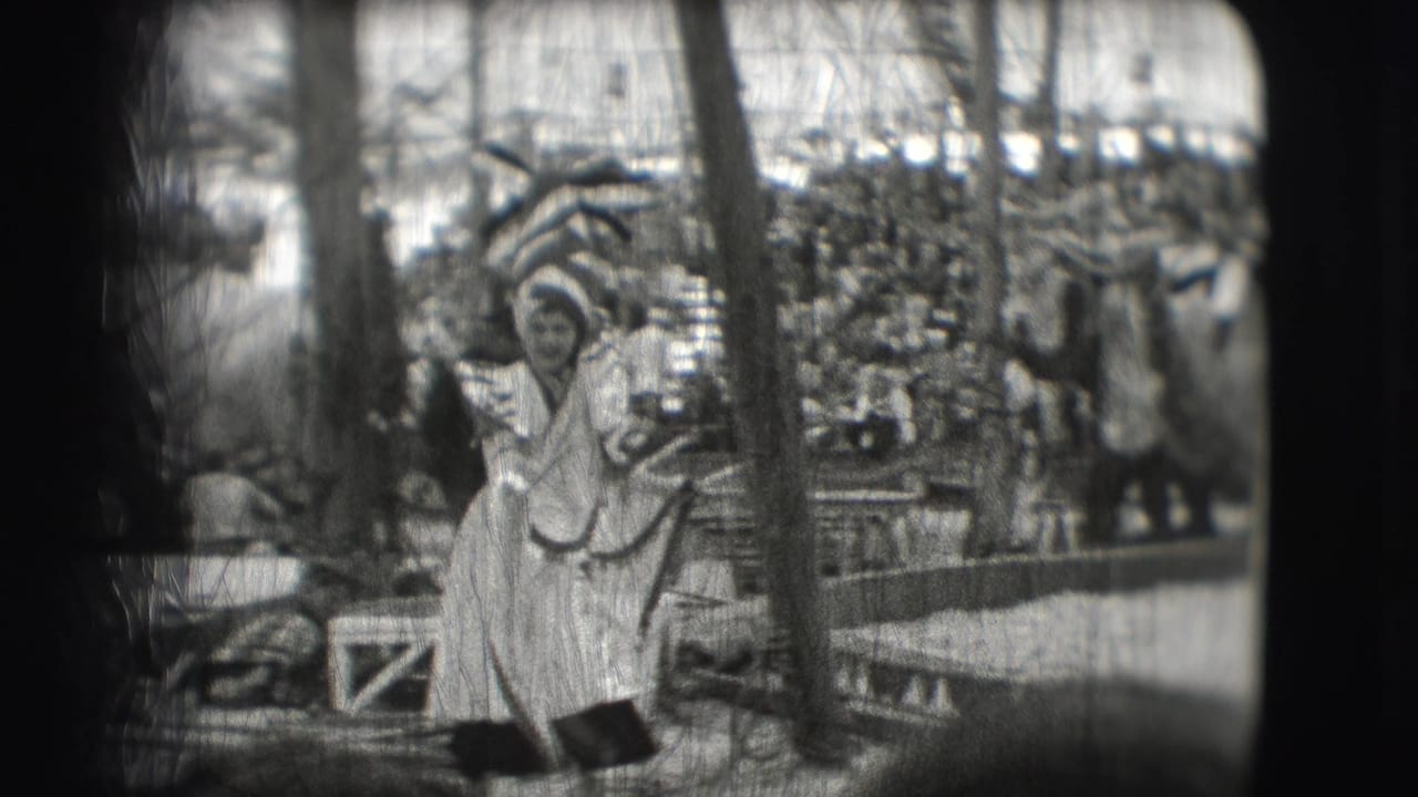 A performer in a light costume stands in the circus ring before a seated crowd.