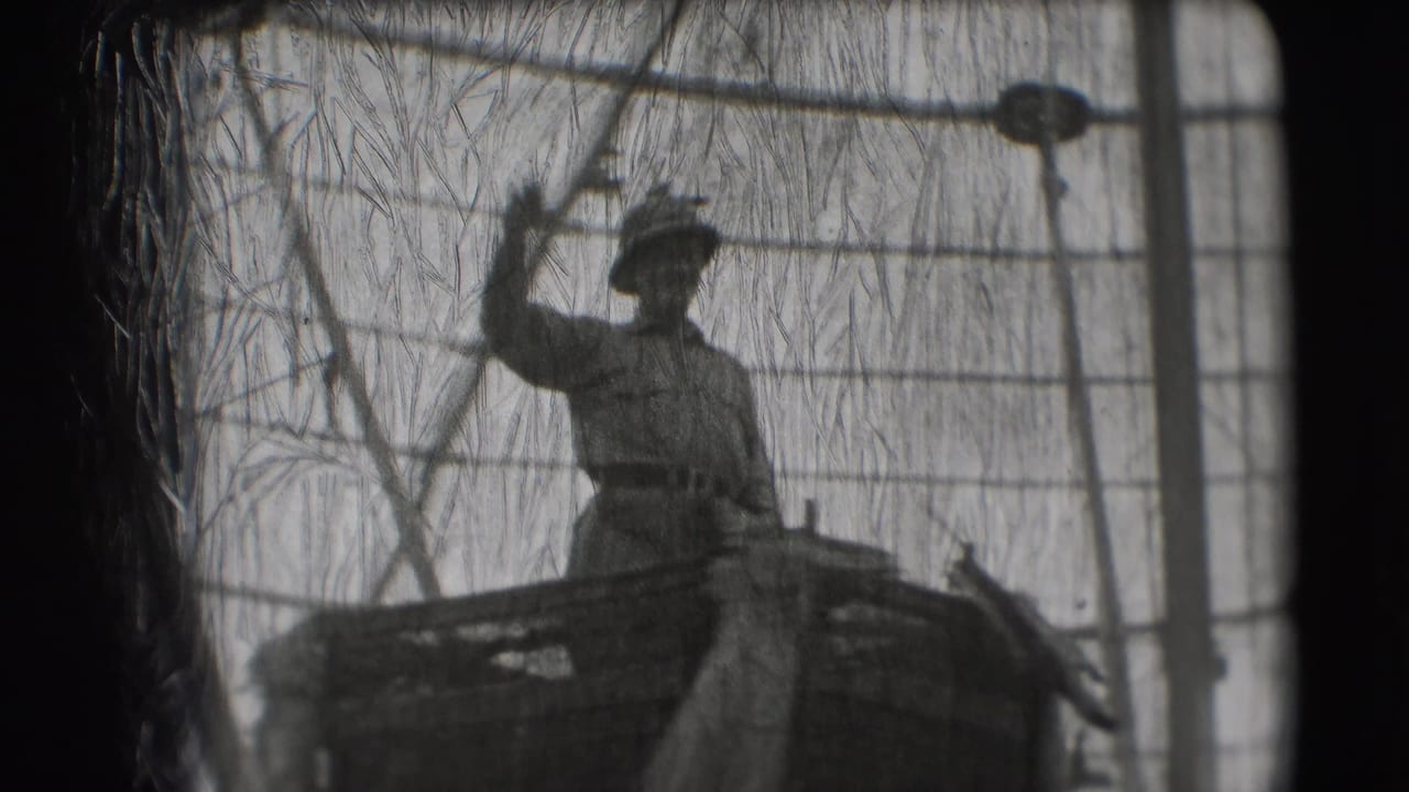 Man in military-style uniform stands on a float with one arm raised behind wire mesh.