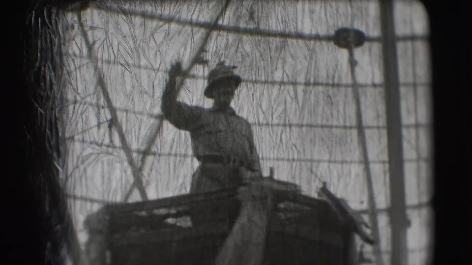 A military-style costumed man on a Ringling Brothers Sarasota float raises his hand while standing behind a visible wire barrier.