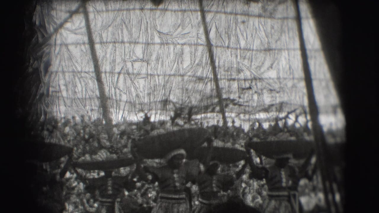 Women performers move in front of a crowded tent audience with objects balanced overhead.