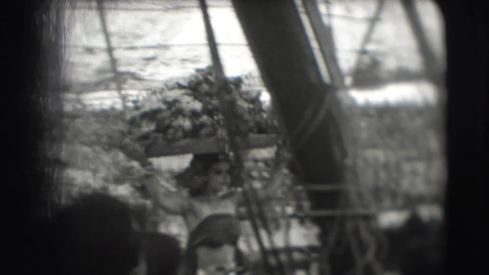Soft 8mm frame showing a woman in performance dress balancing a large object on her head near circus tent supports in Sarasota.