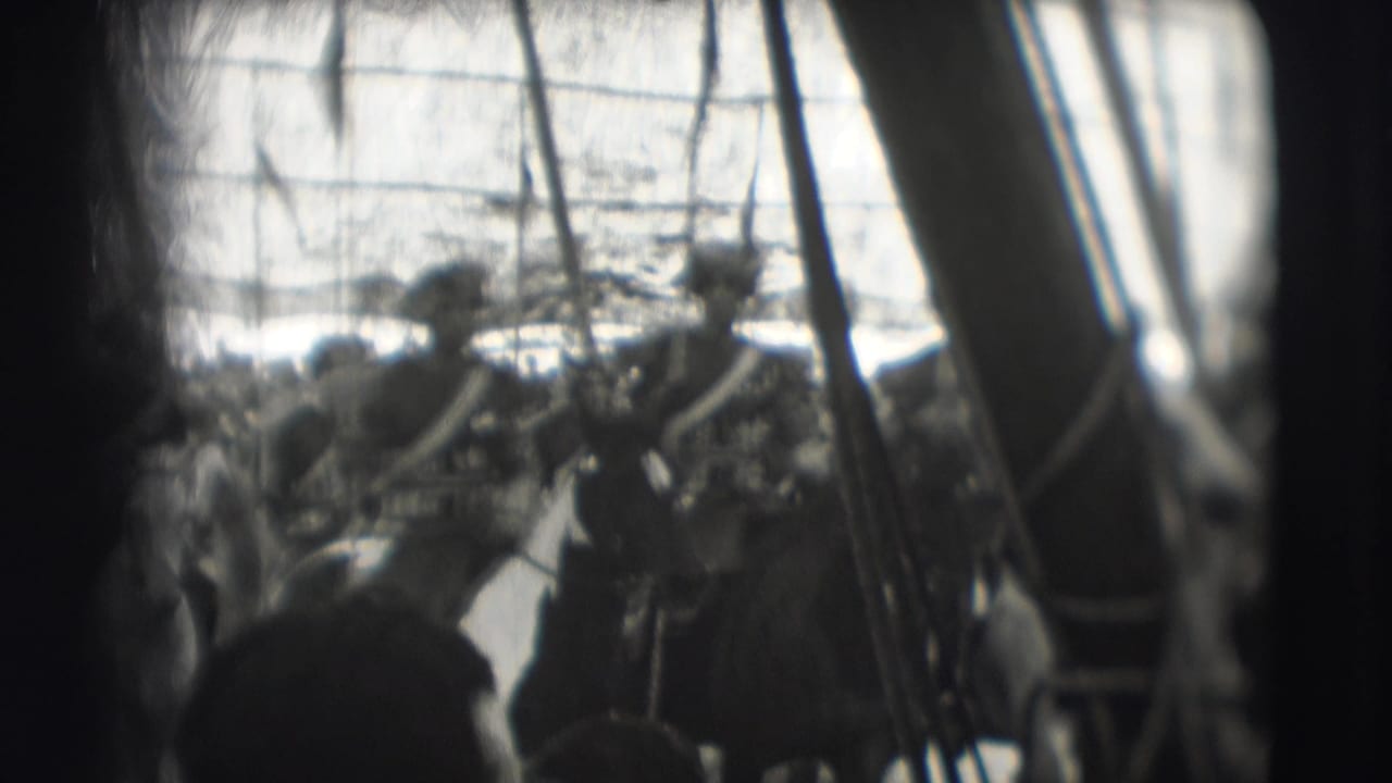 Crowd watches uniformed riders on horseback carrying lances beneath a grid-like overhead structure.