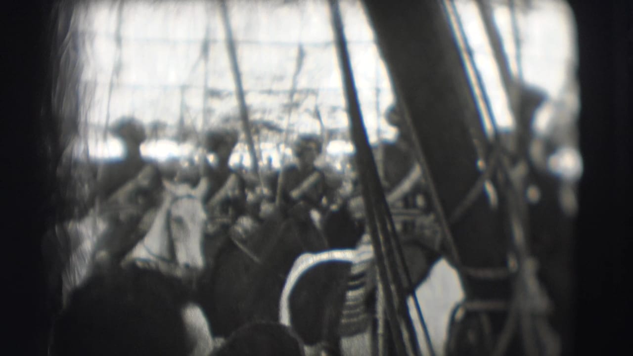 Uniformed horseback riders pass through a crowded parade scene with lances held upright.