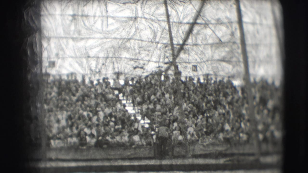 Crowded circus stands seen beyond a rail inside a tented arena.