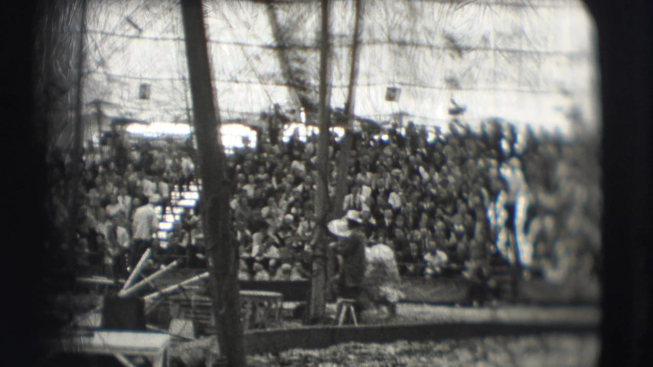 Crowded circus audience viewed across a ring under a tent.
