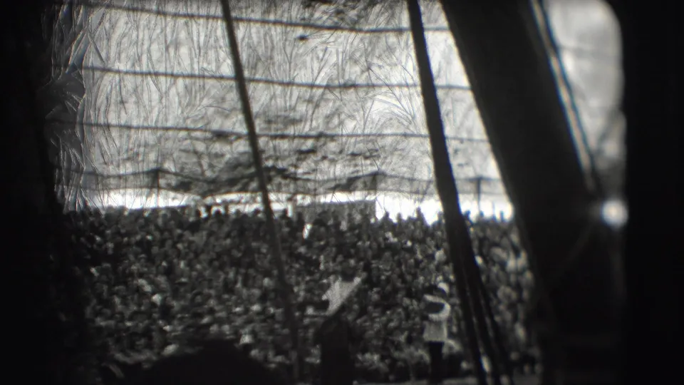 A packed audience watches under the Ringling Brothers big top in Sarasota, with tent supports and performance rigging crossing the frame.