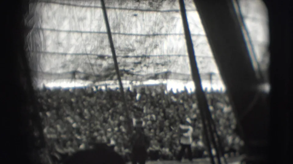1948 Sarasota circus tent view with a dense audience beneath canvas, partly obscured by dark poles and gate framing.