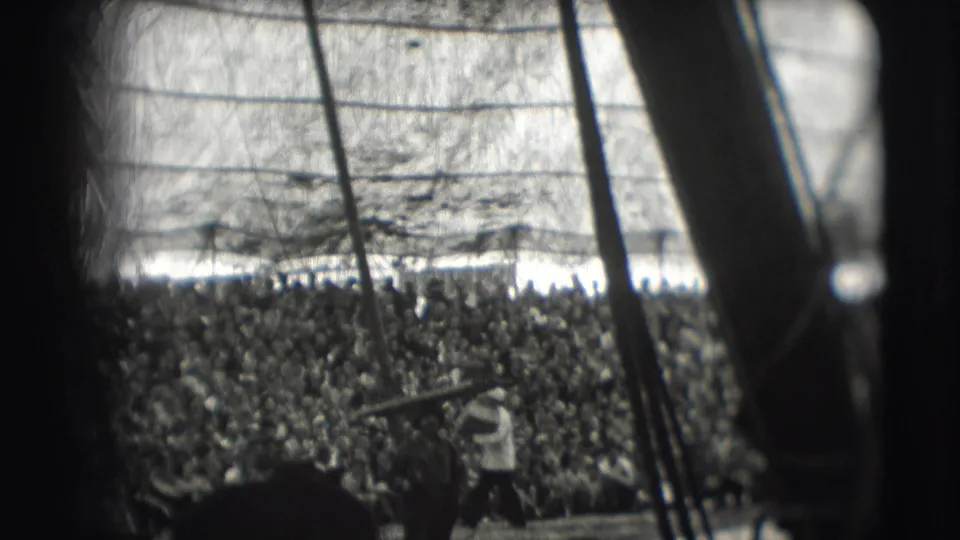 Dense Ringling Brothers Sarasota audience under tent canvas, seen in soft black-and-white 8mm with poles in foreground.