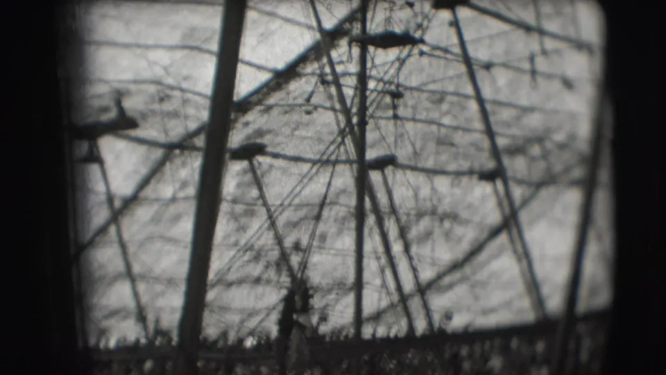 Obstructed 8mm view inside the Sarasota circus tent with rigging, poles, and a packed audience visible below.