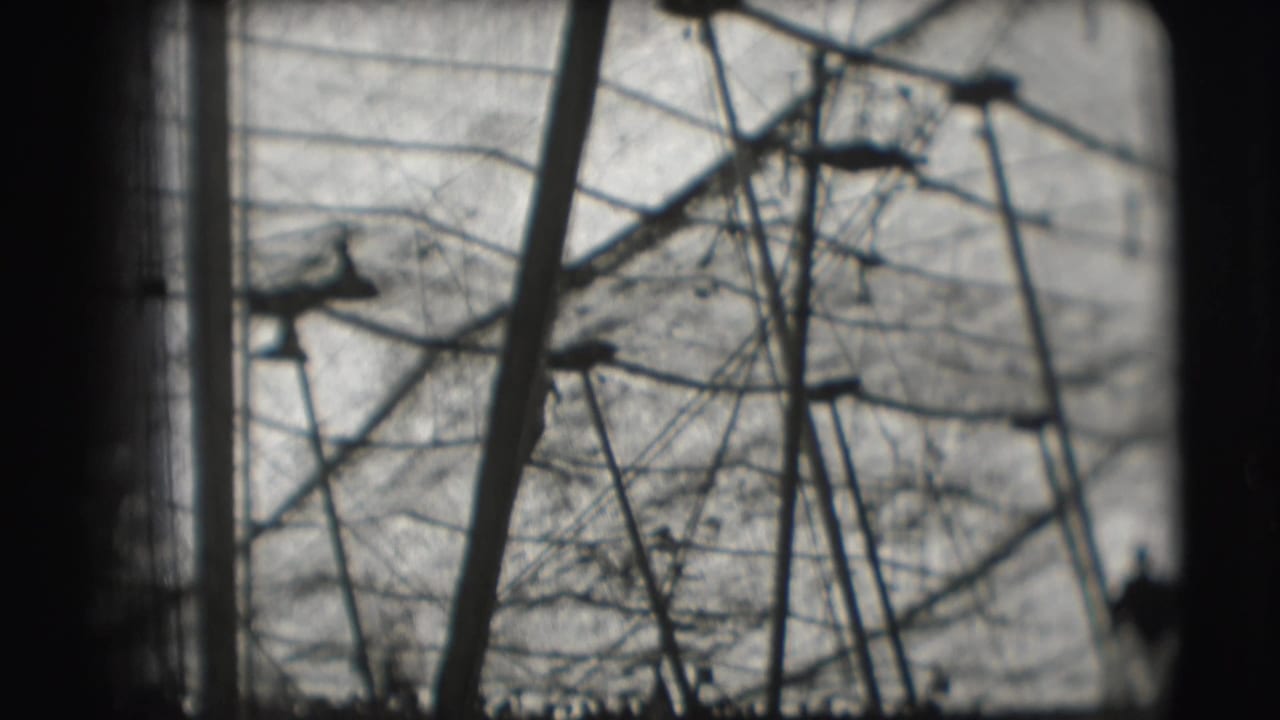 1948 Sarasota circus footage showing a distant silhouetted aerial performer among ropes and poles against a bright sky.