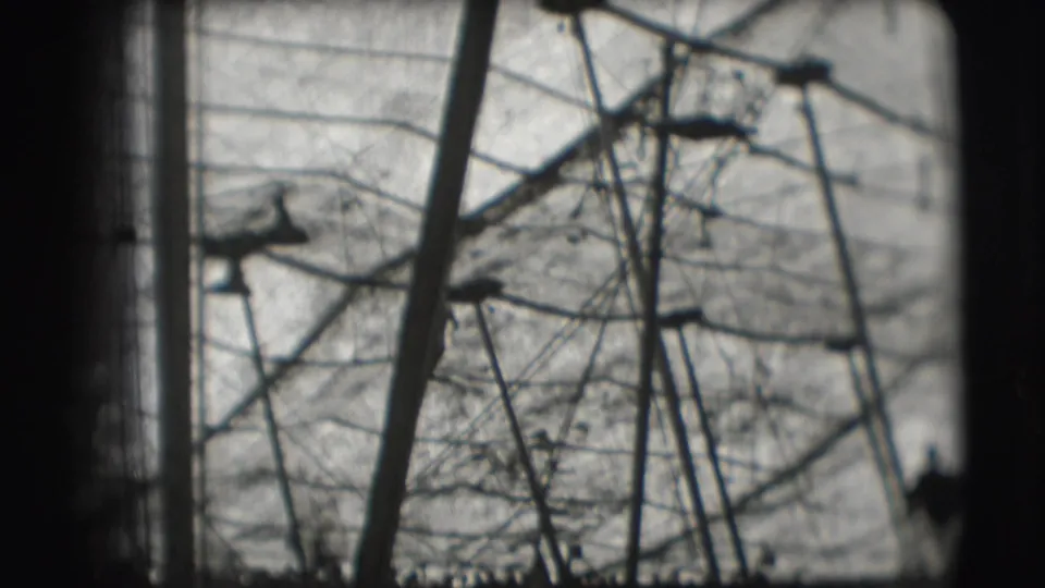 1948 Sarasota circus footage showing a distant silhouetted aerial performer among ropes and poles against a bright sky.