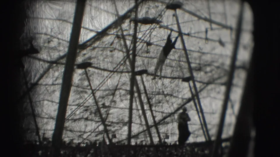 Black-and-white 1948 Sarasota circus frame with a distant silhouetted performer beneath ropes, poles, and aerial apparatus.