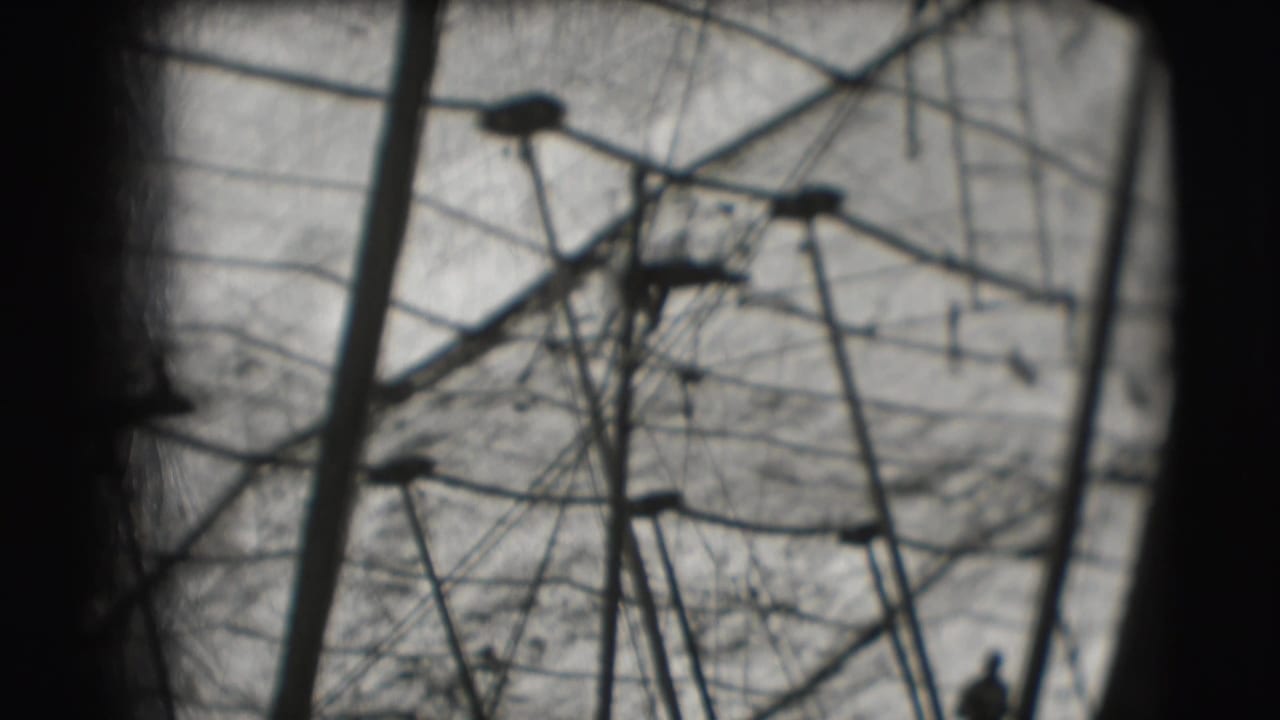 The acrobat appears small against the high tent structure, with wires and poles filling the 8mm frame.