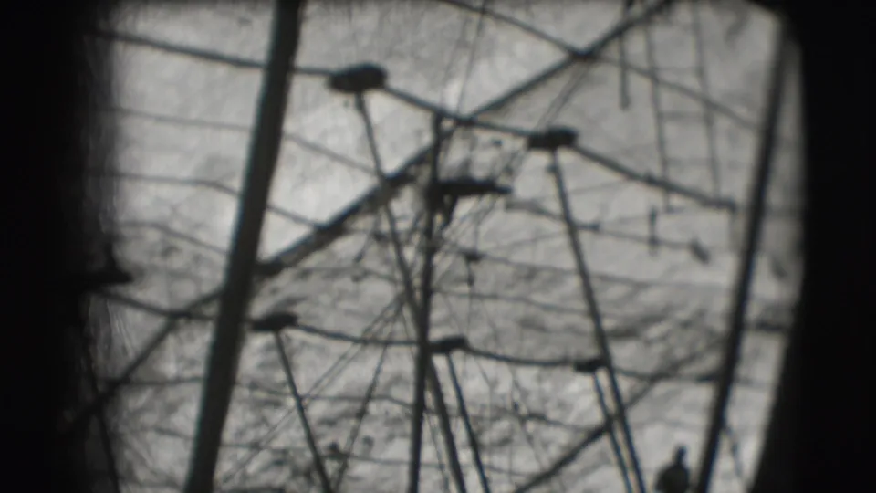 The acrobat appears small against the high tent structure, with wires and poles filling the 8mm frame.