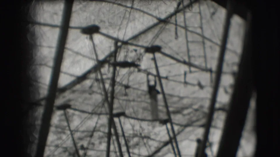 A soft, grainy 1948 circus frame shows the high apparatus and a small silhouetted acrobat below the rigging.