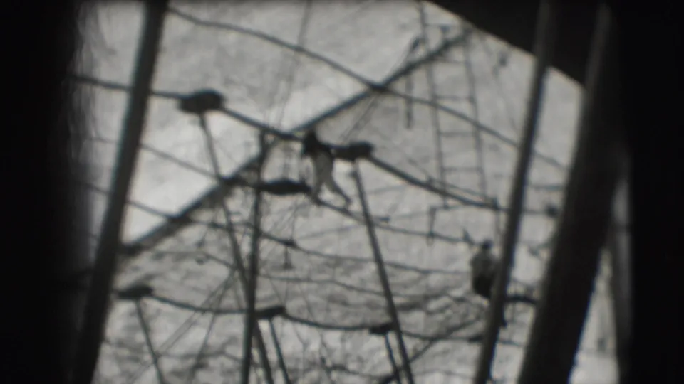 1948 Sarasota circus footage shows a small acrobat form near upper rigging, with ropes and poles filling the frame.