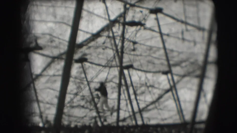 1948 Ringling Brothers Sarasota frame showing the acrobat as a dark silhouette below the high-bar rigging and netted backdrop.