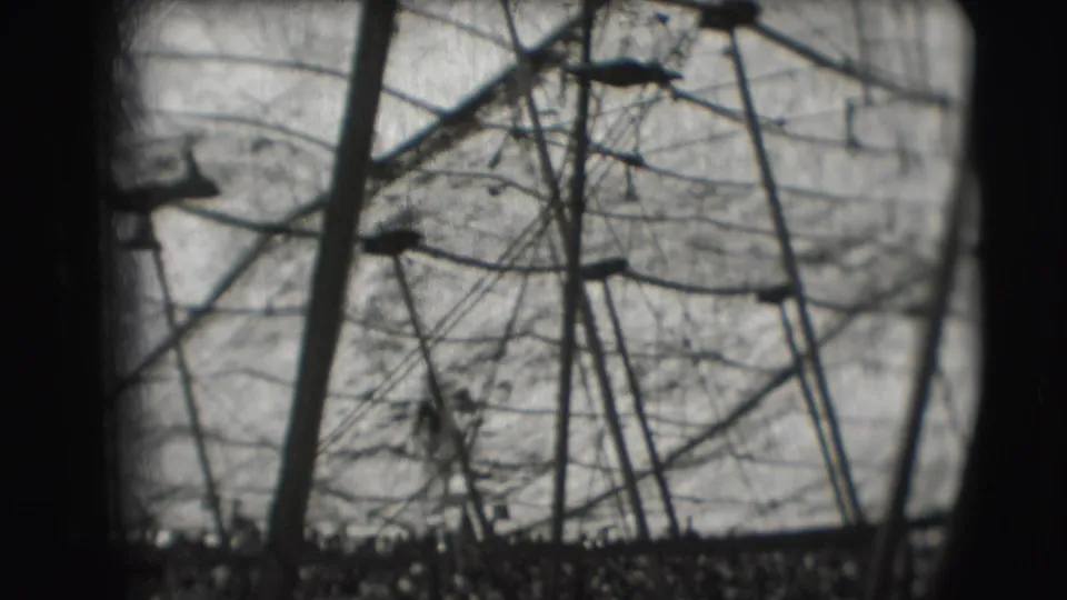 1948 Sarasota circus footage shows a small silhouetted performer rotating near high-bar rigging and support poles.