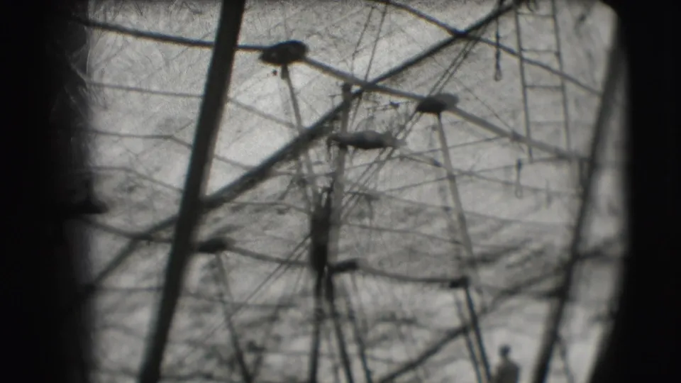 A silhouetted acrobat appears beside high circus rigging in black-and-white 8mm footage from Sarasota.