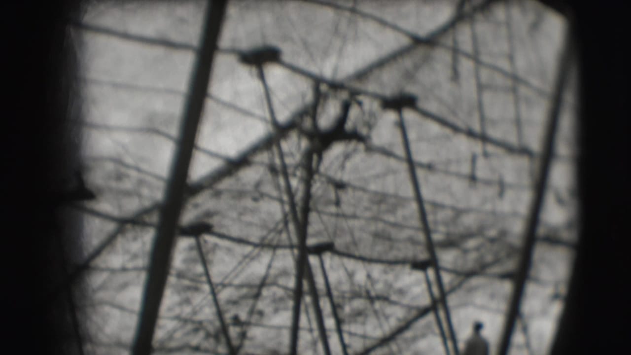 1948 Sarasota circus home-movie frame showing tent poles, wires, and canvas through a dark rounded vignette.