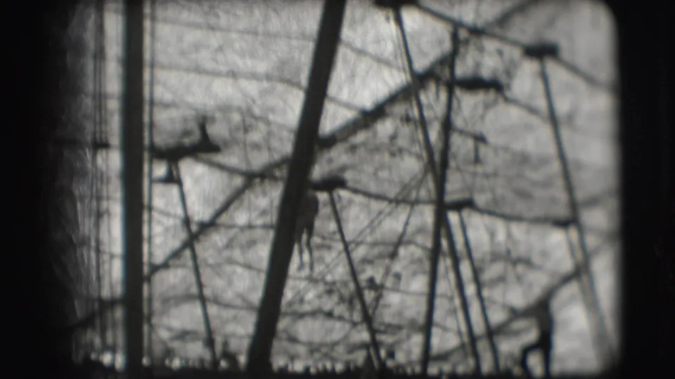 1948 Sarasota circus footage showing a distant acrobat near high bar rigging, support poles, netting, and bare branches.