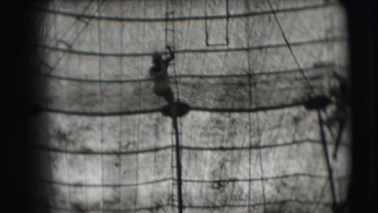 A distant acrobat is silhouetted on the trapeze structure in black-and-white 1948 Sarasota circus footage.