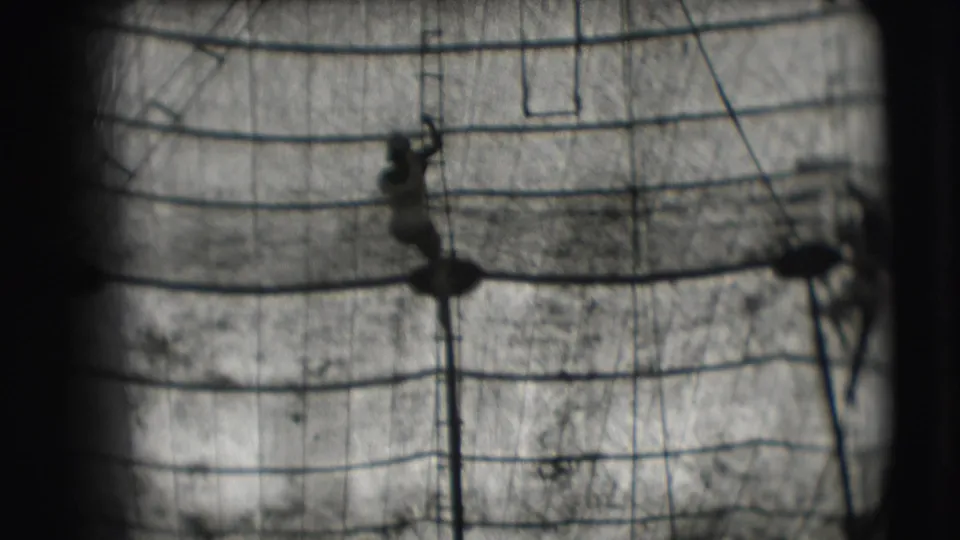 A distant acrobat is silhouetted on the trapeze structure in black-and-white 1948 Sarasota circus footage.