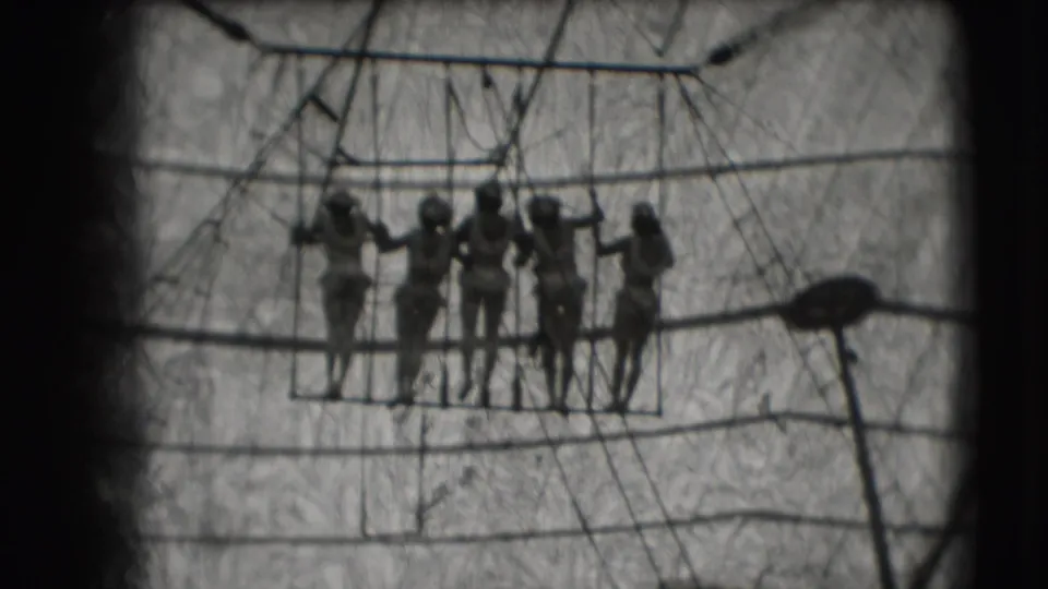 Women performers line up on the trapeze apparatus beneath canvas and rigging in the Ringling Brothers Sarasota clip.