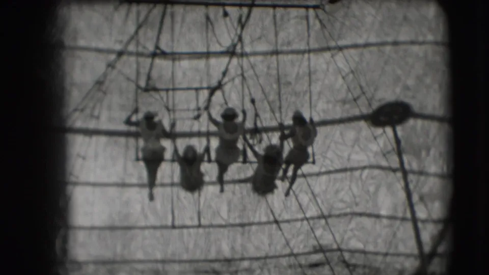 1948 Sarasota circus footage showing multiple trapeze performers silhouetted near bars, ropes, and tent canvas.