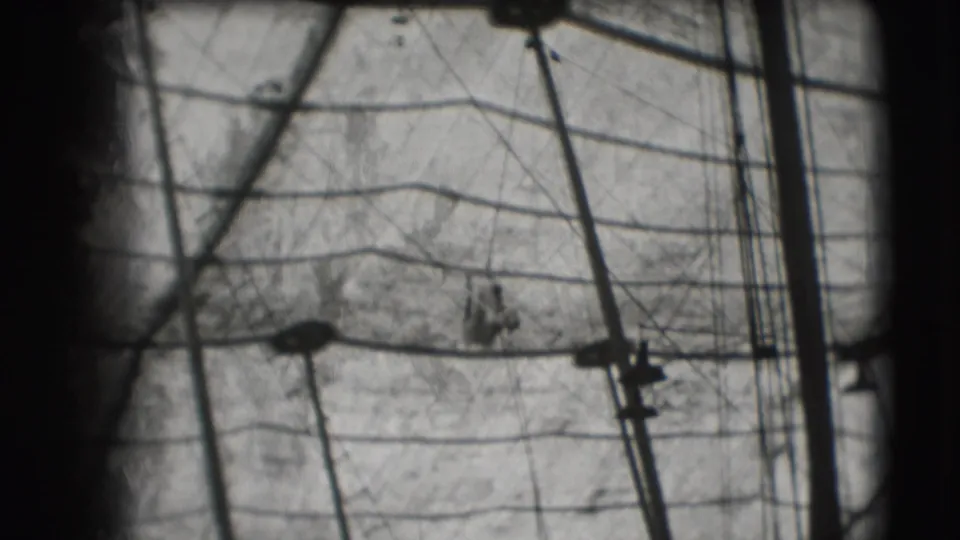1948 Sarasota circus frame with trapeze rigging, tent canvas, and a small performer silhouette near the lower right.