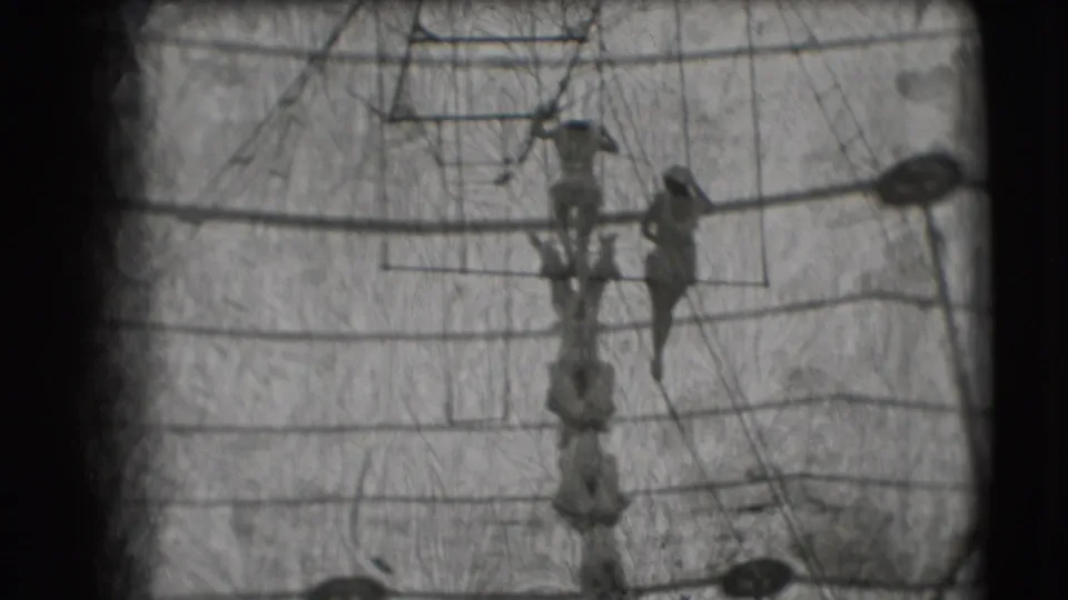 1948 Sarasota circus footage showing two distant trapeze performers suspended near rigging inside the tent.