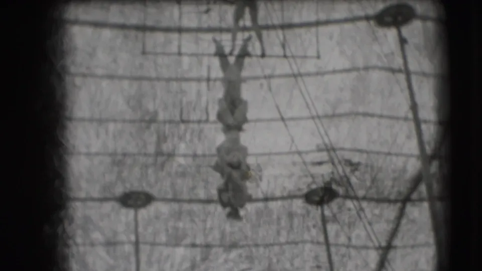 Acrobats form a hanging chain under the circus rig in this black-and-white 8mm frame from the Sarasota Ringling footage.