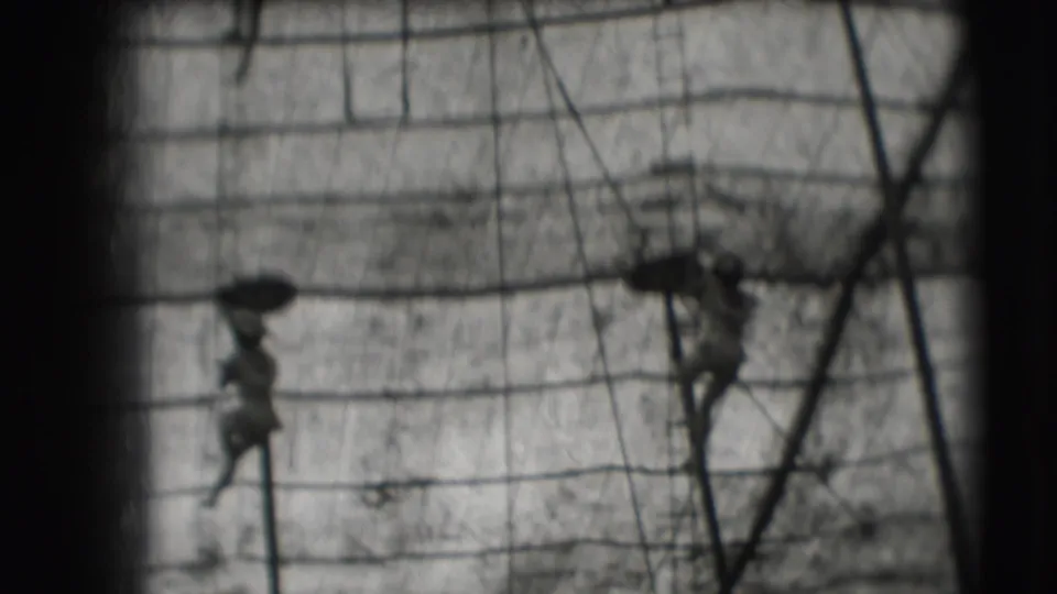 Two distant figures move through lower ship-like rigging in grainy black-and-white 8mm footage tied to Sarasota metadata.