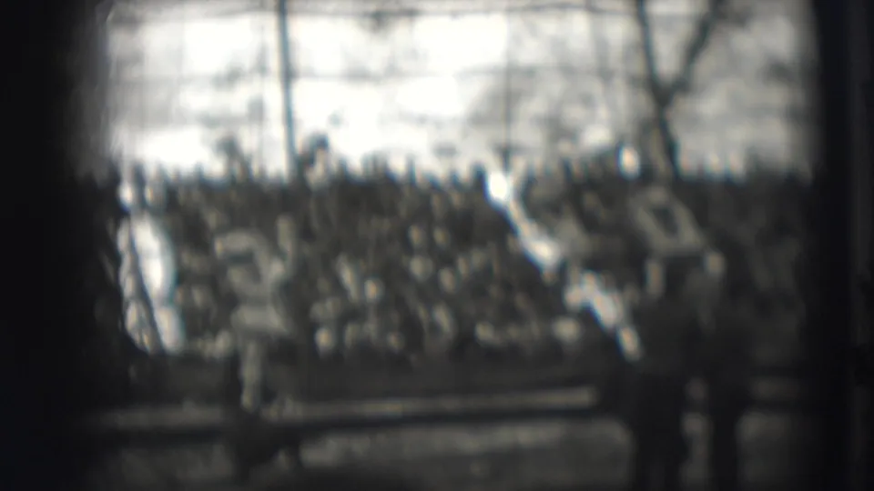 The view shifts toward the seated crowd and tent interior, with rope-act activity softened by blur and foreground obstruction.