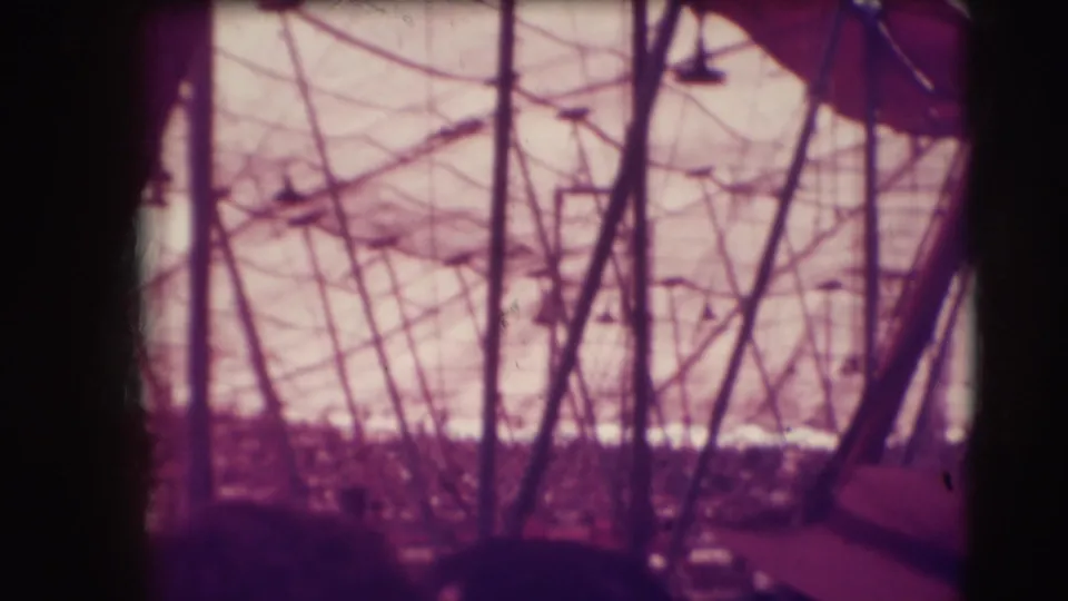 Color-tinted 8mm view of circus tent poles, rigging, and audience silhouettes in Sarasota footage.