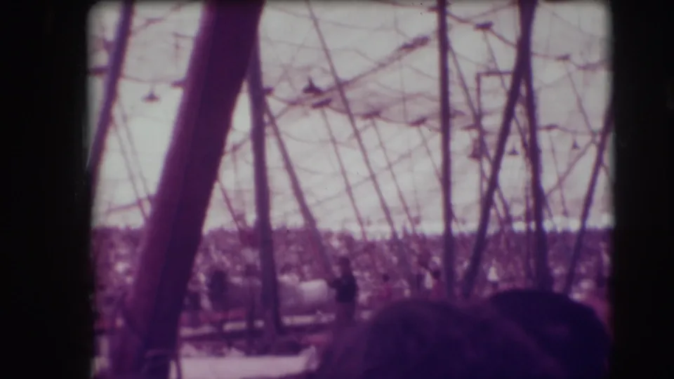 Sarasota Ringling Brothers big-top scene with tent poles, rigging, audience seating and foreground spectators in aged 8mm color.