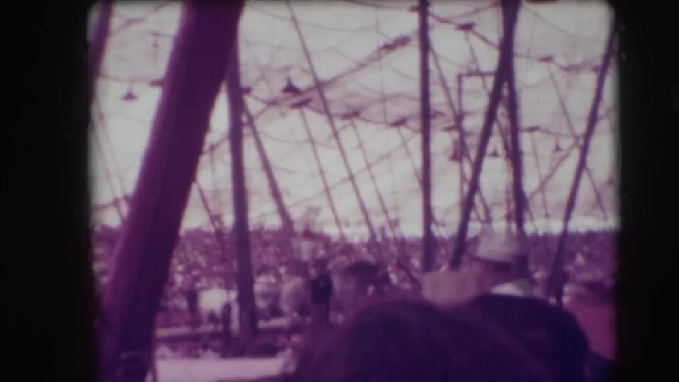 Audience-shot 1948 Sarasota circus frame showing a rider on horseback amid tent poles, ropes, and crowded seating.