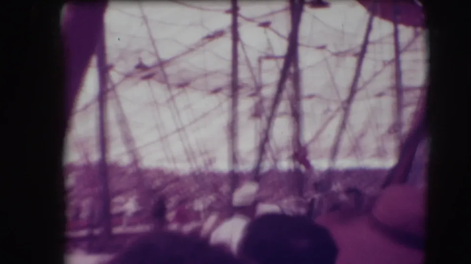 Soft 8mm frame from the Sarasota circus showing tent structure, crowd, and a partly hidden horse act behind spectators.