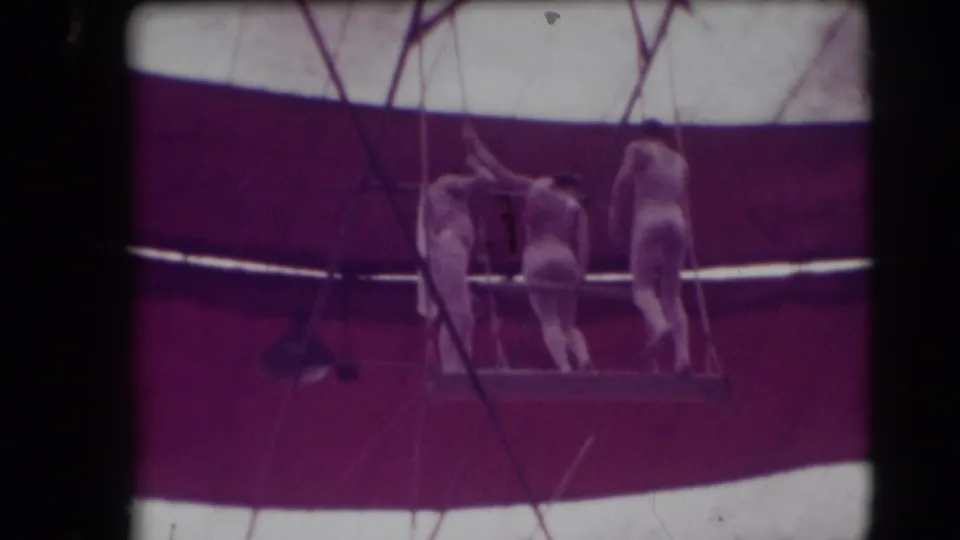 1948 Sarasota circus frame showing performers on an elevated trapeze platform beneath the striped tent canopy.