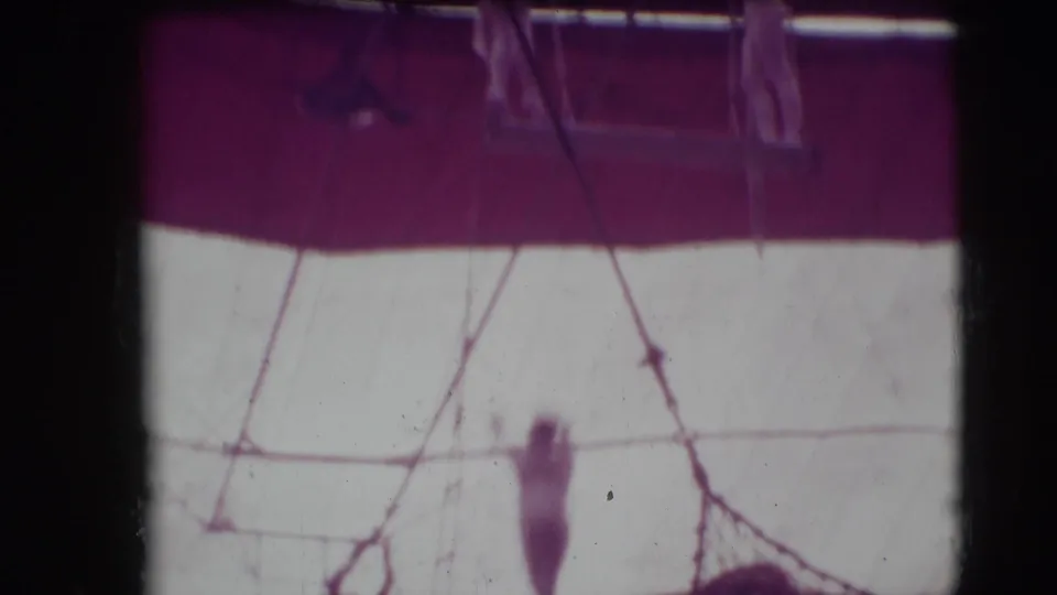 1948 Sarasota circus footage appears to show a small aerial performer near trapeze rigging inside a tent.