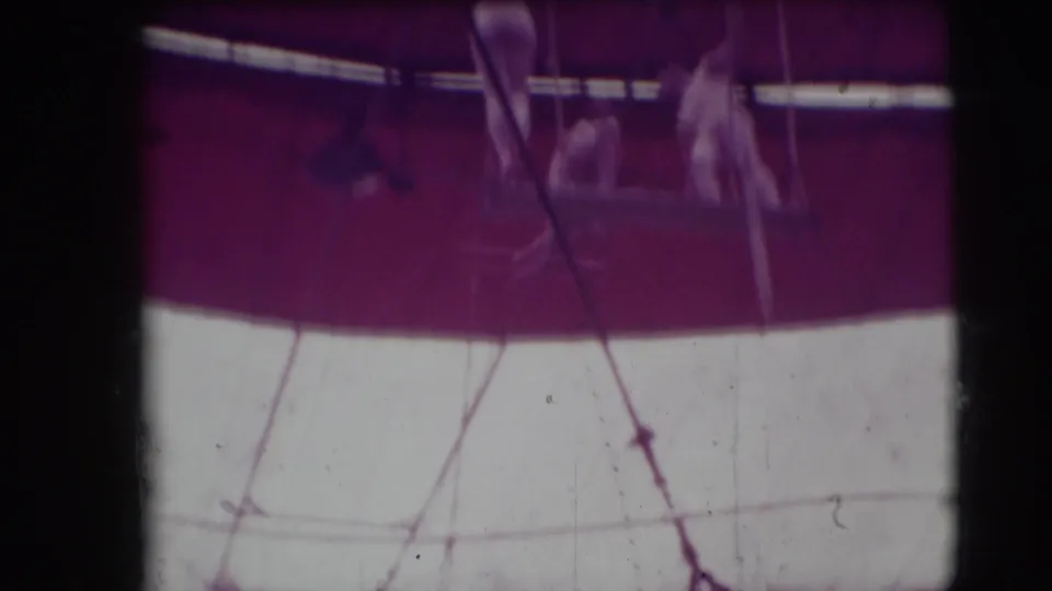 Distant circus acrobats appear on a high platform beneath purple and white tent fabric in the 1948 Sarasota footage.