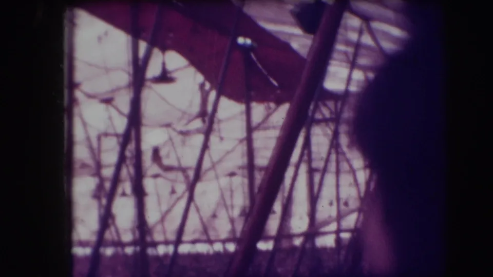 Purple-tinted 1948 home-movie frame showing circus rigging or netting through dark edge shadows in Sarasota metadata context.